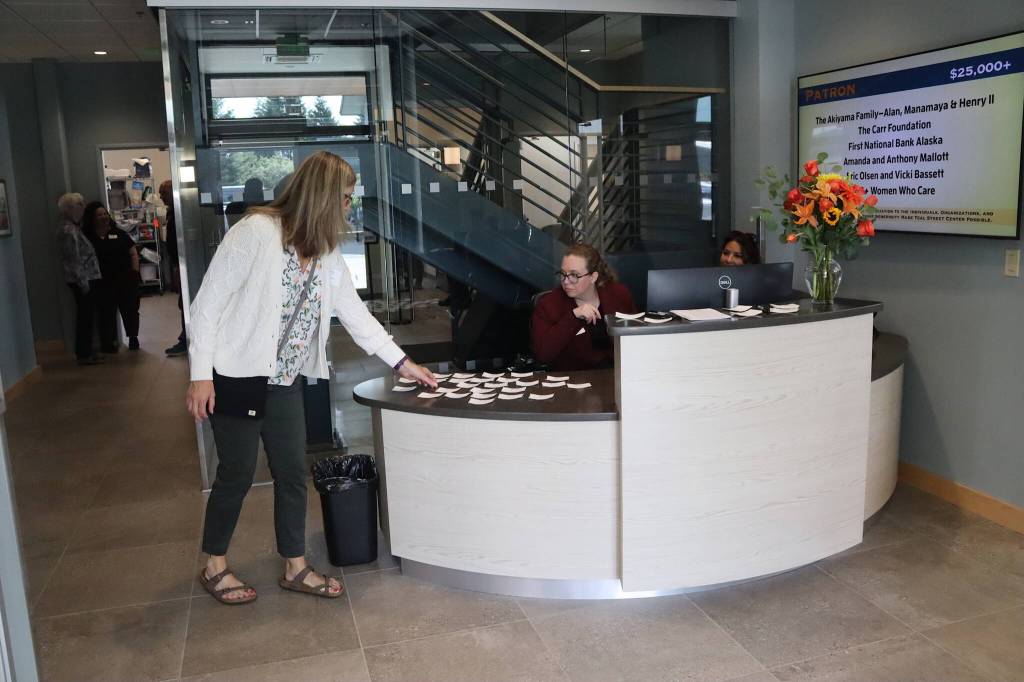 A guest picks up their name tag from the reception desk at the Teal Street Center during a ribbon-cutting ceremony Thursday afternoon. (Mark Sabbatini / Juneau Empire)