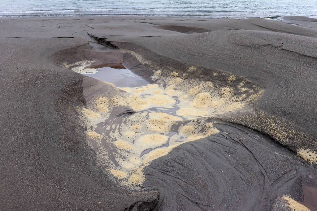 A sulfide scum filled hole is left behind on the Sheep Creek Delta after hydro dredging. (Jasz Garrett / Juneau Empire)