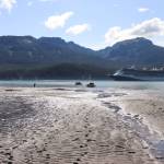 A young girl plays on the Sheep Creek delta near suction dredges while a cruise ship passes the Gastineau Channel on July 20. (Jasz Garrett / Juneau Empire)