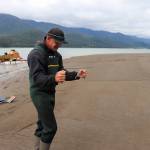 Ernest Hart uses dowsing rods to locate gold on the Sheep Creek delta on Monday. (Jasz Garrett / Juneau Empire)