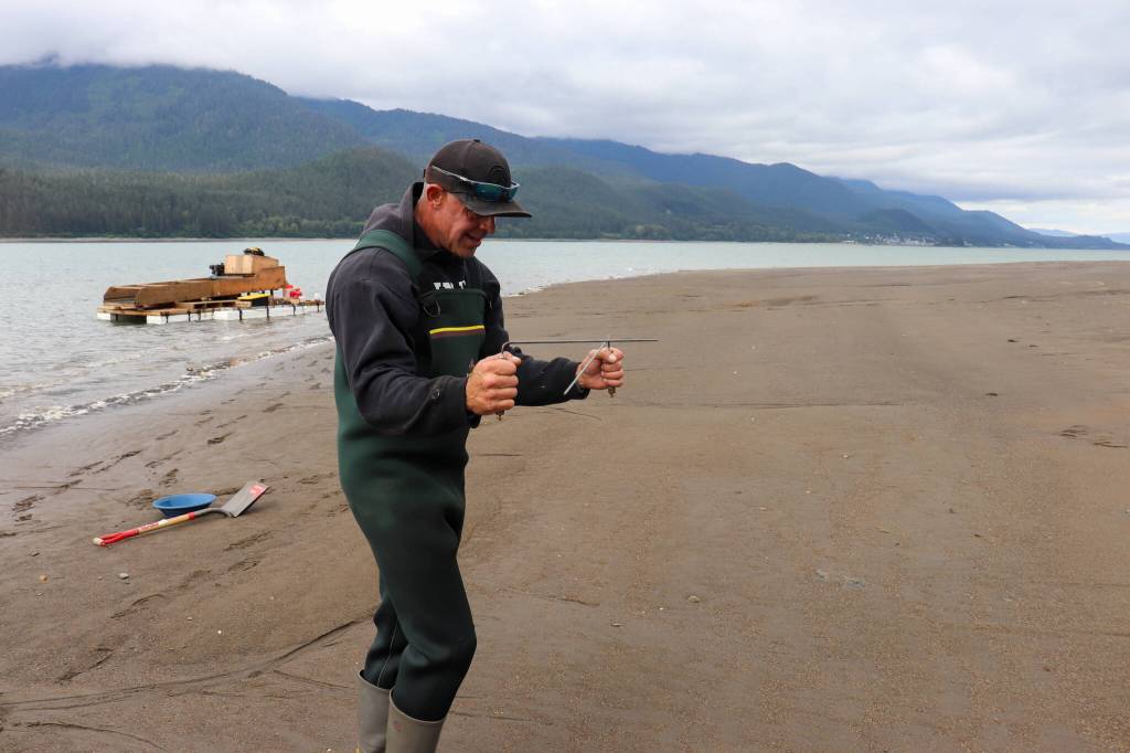 Ernest Hart uses dowsing rods to locate gold on the Sheep Creek delta on Monday. (Jasz Garrett / Juneau Empire)