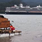 A salmon jumps near a suction dredge on Monday while a cruise ship departs Juneau in Gastineau Channel. (Jasz Garrett / Juneau Empire)