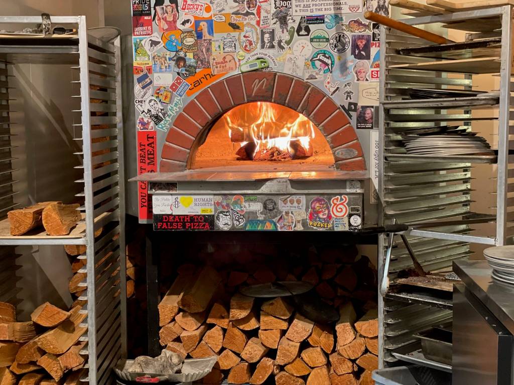 Flames rise in the wood-fired pizza oven inside In Bocca Al Lupo. (Laurie Craig / Juneau Empire)
