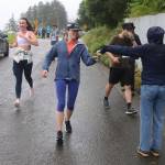 People participating in the Juneau Half Marathon pass by an aid station near the Douglas Bridge on Saturday. (Mark Sabbatini / Juneau Empire)