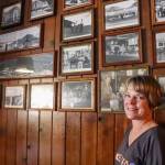 Leeann Thomas, owner of the Triangle Club for the last 25 years, stands with a wall of historic photos from her family albums and the Alaska State Museum on Tuesday. (Jasz Garrett / Juneau Empire)