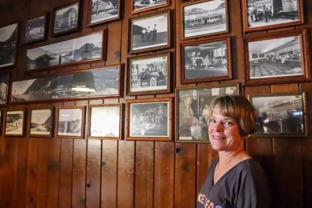 Leeann Thomas, owner of the Triangle Club for the last 25 years, stands with a wall of historic photos from her family albums and the Alaska State Museum on Tuesday. (Jasz Garrett / Juneau Empire)