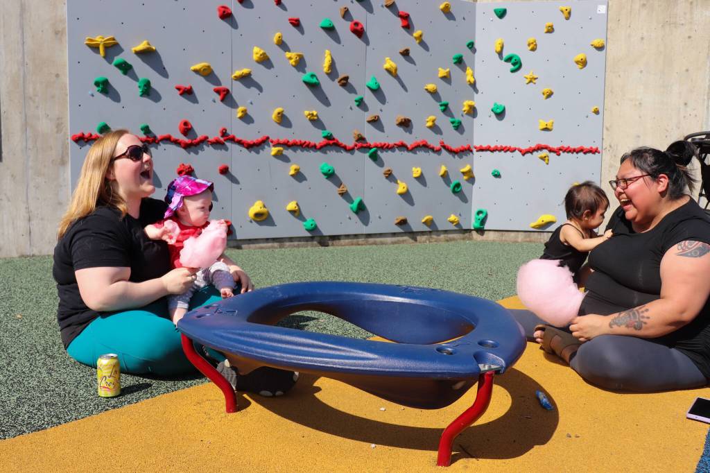Jennifer Parkin and Rose McLean play with their babies in an area reserved for young children at Capitol Park on Saturday. (Jasz Garrett / Juneau Empire)