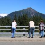 People watch the Mendenhall River from a bridge on Back Loop Road early Sunday afternoon, a few hours after the break of Suicide Basins ice dam. The river level of about five feet Sunday morning is forecast to peak at about 15 feet at 4 a.m. Tuesday. (Mark Sabbatini / Juneau Empire)