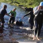 Volunteers help swimmers out of the 62-degree water at Auke Lake during the Aukeman Triathlon on Sunday, (Mark Sabbatini / Juneau Empire)