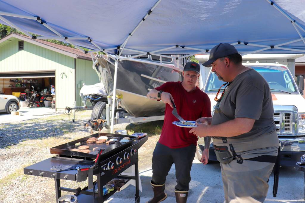 Dustin McCoy, a secretary for the U.S. Coast Guard in Southeast Alaska, gives a burger to Emily Way resident Neil Stichert on Wednesday. (Jasz Garrett / Juneau Empire)