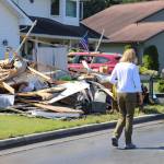 U.S. Sen. Lisa Murkowski walks past a home on Killewich Drive with damaged items left outside in the sun on Wednesday. (Jasz Garrett / Juneau Empire)