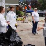 Volunteers Heidi Cope (left) and James Currie wear full-body protective suits as they discuss clearing out insulation and other hazardous material from the flooded crawlspace of a flooded home during a visit Sunday by officials including U.S. Rep. Mary Peltola. (Mark Sabbatini / Juneau Empire)