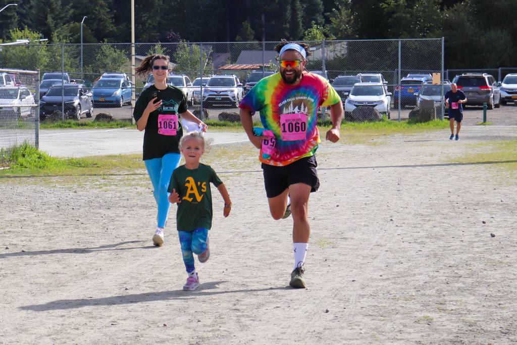 Stefanie Bouma, Ephraim Froehlich and Oromo Bouma run toward the finish line in Cancer Connections 33rd annual Beat the Odds: A Race Against Cancer on Saturday. (Jasz Garrett / Juneau Empire)