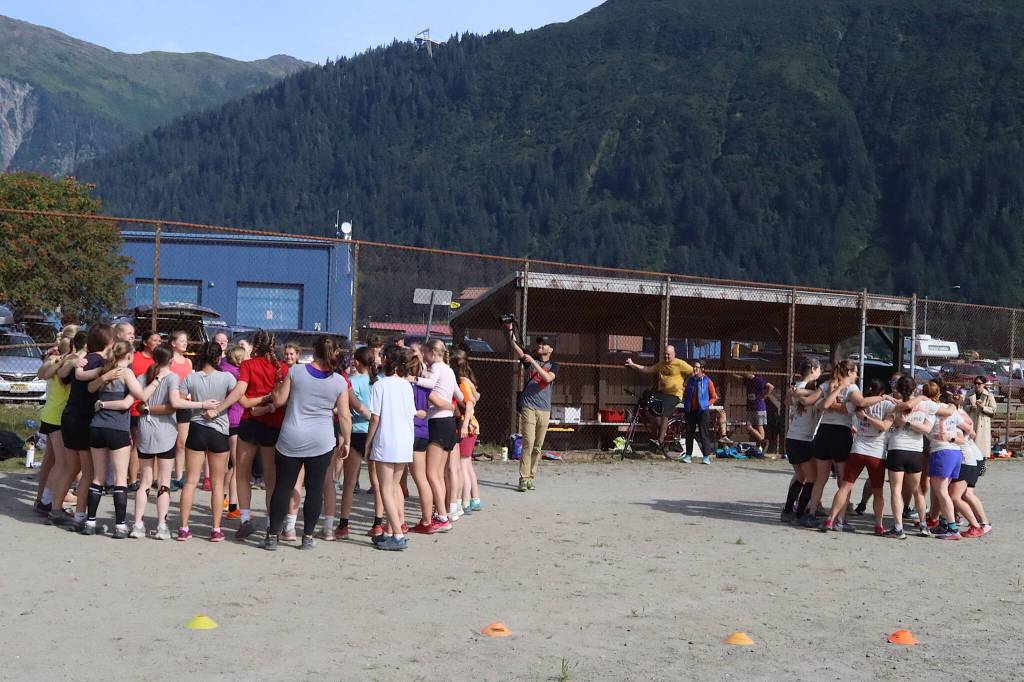 Members of the girls cross-country team at Juneau-Douglas High School: Yadaa.at Kalé (left) and alumni of local cross-country teams form separate rally circles before the womens 5K race of the Sayéik Invitational at Savikko Park on Saturday morning. (Mark Sabbatini / Juneau Empire)