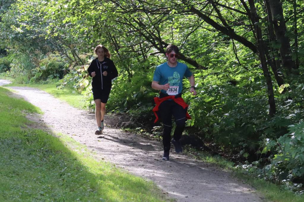 Participants in the Sayéik Invitational on Saturday warm up before their 5K race on the Treadwell Historic Mine Trail. (Mark Sabbatini / Juneau Empire)