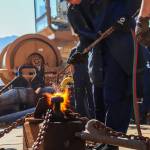District 13 seaman Hailey Crawford from the U.S. Coast Guard cutter Henry Blake uses a blowtorch on Wednesday in the heat-and-beat competition, the end of the Buoy Tender Olympics, an annual buoy tender round-up at U.S. Coast Guard Station Juneau. (Jasz Garrett / Juneau Empire)