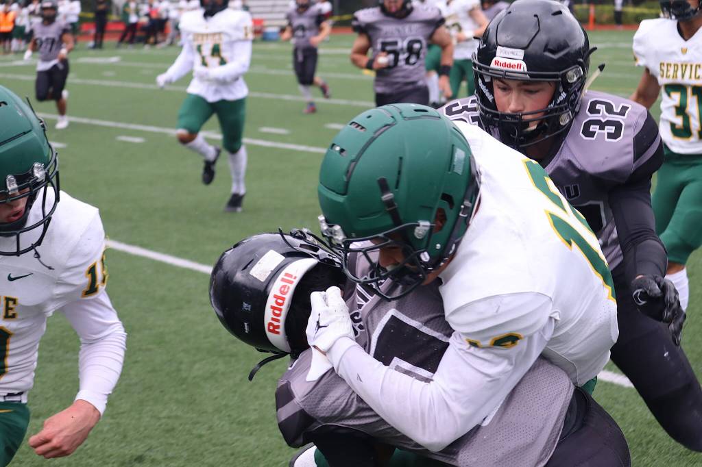 Noah Ault (1), a junior quarterback for Juneau-Douglas High School: Yadaa.at Kalés, is injured by a hard hit from a Service High School defender during the first quarter of Saturdays game at Adair-Kennedy Memorial Park. (Mark Sabbatini / Juneau Empire)