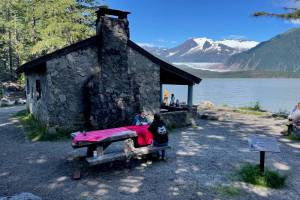 A gathering of friends rent Skaters Cabin on Mendenhall Lake from the U.S. Forest Service on a sunny day in July of 2024. The cabin and the West Glacier Trail beyond it were Civilian Conservation Corps projects. (Laurie Craig / Juneau Empire)