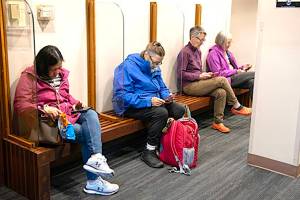 Sitkans sit in the lobby of city hall on Saturday as they use the citys satellite connection to the internet with their cell phones. (Sitka Sentinel photo)