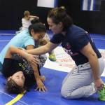 Mallory Velte, a professional wrestling coach, shows a technique to Ciara Dutton (wearing blue) and Haylee Ondrejka during a wrestling camp Sept. 1 at the Juneau Wrestling Center. (Mark Sabbatini / Juneau Empire)