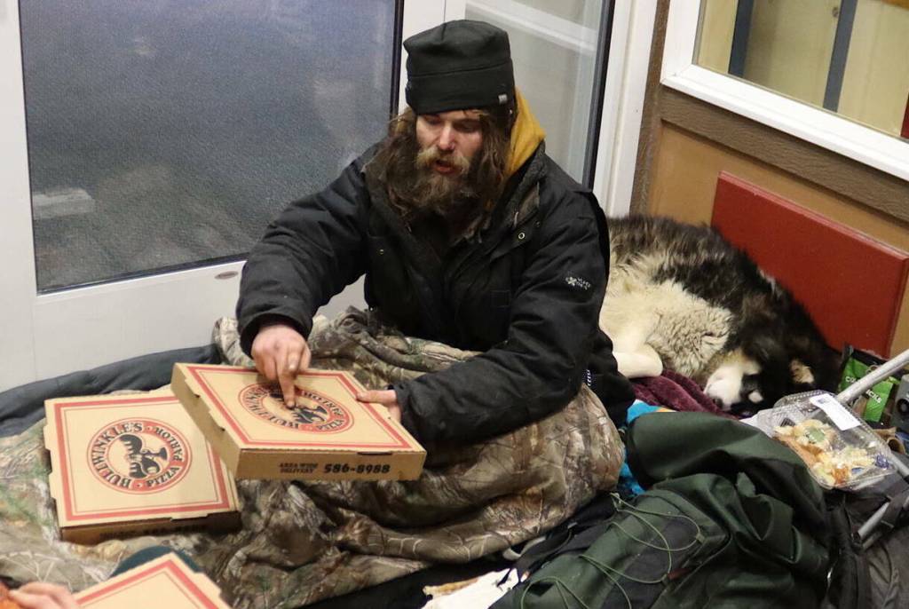 Steven Kissack and his dog, Juno, take shelter in the doorway of the Front Street Clinic building on Dec. 24, 2023. (Mark Sabbatini / Juneau Empire file photo)