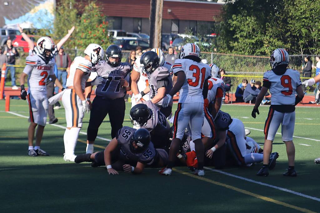 An official signals a touchdown as Samuel Sarof (27) barely makes it across the goal line for Juneau-Douglas High School: Yadaa.at Kalé in the first half of Saturdays game against West Anchorage High School at Adair-Kennedy Memorial Park. (Mark Sabbatini / Juneau Empire)