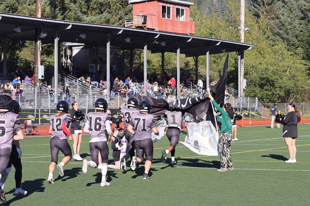 Juneau Huskies players break through a banner as they take the field to start the second half of Saturdays game against West Anchorage High School at Adair-Kennedy Memorial Park. (Mark Sabbatini / Juneau Empire)