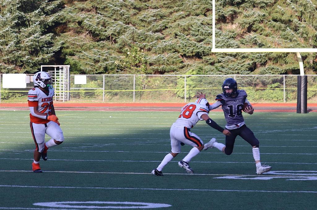 Caleb Ziegenfuss (16) tries to stiff-arm a tackler while trying to rally Juneau-Douglas High School: Yadaa.at Kalé on a final drive in the closing seconds against West Anchorage High School on Saturday at Adair-Kennedy Memorial Park. (Mark Sabbatini / Juneau Empire)