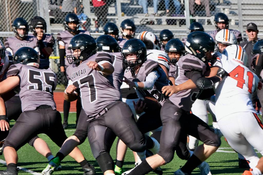 Juneau Huskies senior Caleb Ziegenfuss (16) runs behind the blocking of junior Walter Haube-Law (55), junior Ricky Tupou (77) and senior Johnathyn Kestel (32) during the Huskies 28-27 loss to the West Anchorage High School Eagles on Saturday at Adair-Kennedy Memorial Park. (Klas Stolpe / For the Juneau Empire)
