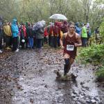 A Hoonah High School runner splashes through a puddle on the Treadwell Mine Historic Trail during the Capital City Invite 5K on Saturday. (Mark Sabbatini / Juneau Empire)