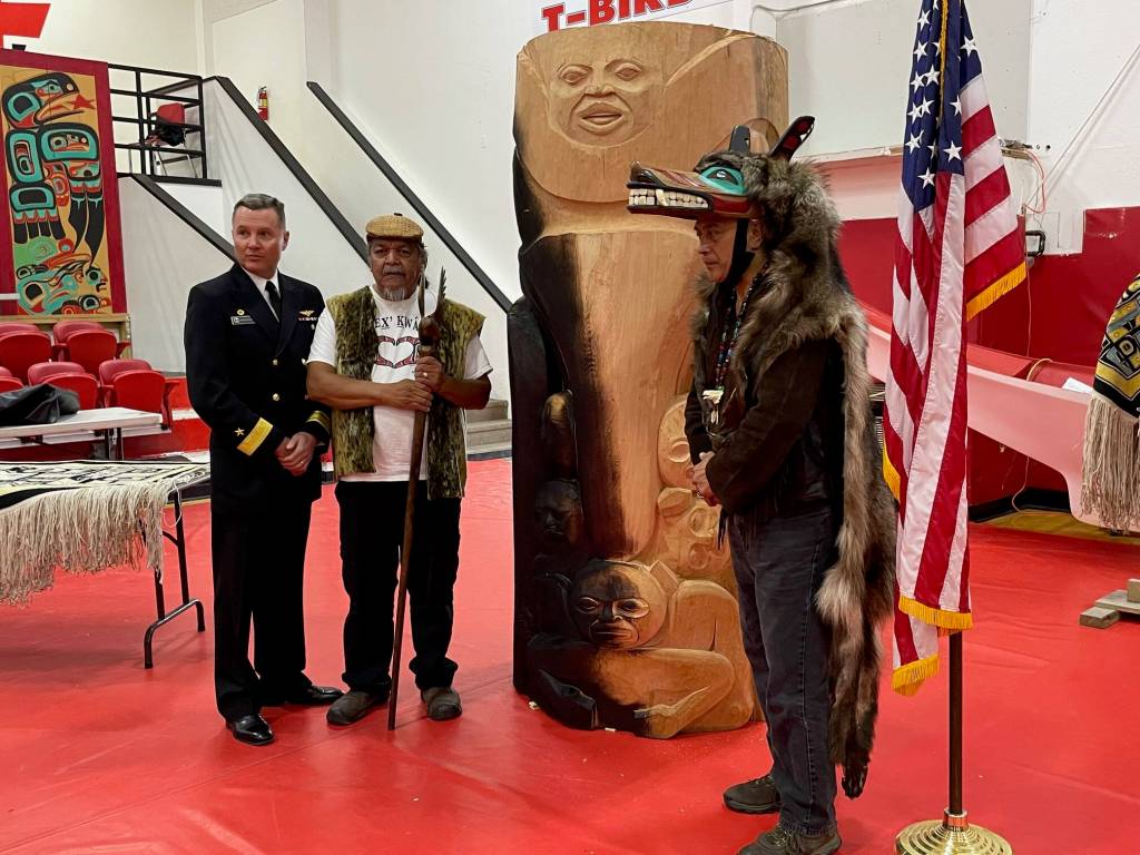 Rear Adm. Mark Sucato, Paul Aceveda and Ben Coronell stand beside Rob Mills totem pole base that was intentionally blackened by fire to represent the burning of Kake in 1869 during a ceremony on Saturday where the U.S. Navy apologized for the attack. (Laurie Craig / Juneau Empire)