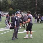 Juneau Huskies Head Coach Rich Sjoroos congratulates senior lineman Stefano Rivera, one of nine Juneau Huskies seniors honored before Saturdays game against Bartlett High School at Adair-Kennedy Memorial Park. (Mark Sabbatini / Juneau Empire)