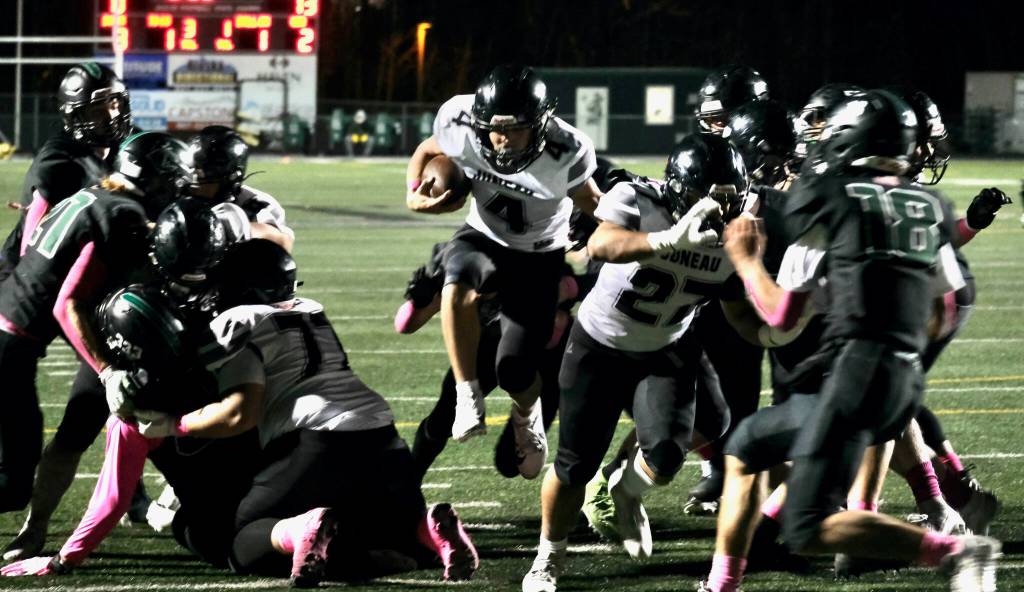 Juneau senior Jayden Johnson (4) leaps over the goal line behind blocks by juniors Ricky Tupou (77), left, and Samuel Sarof (27), right, during the Huskies 42-6 win over the Knights on Friday in Palmer. (Klas Stolpe / Juneau Empire)