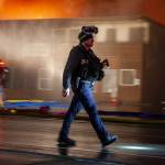 Haines Borough police officer Michael Fullerton helps with crowd control as firefighters battle a fire at the building that houses the Quickshop convenience store, a liquor store, and outdoor store and a handful of apartments on Saturday, Oct. 5, 2024, in Haines. (Rashah McChesney/Chilkat Valley News)