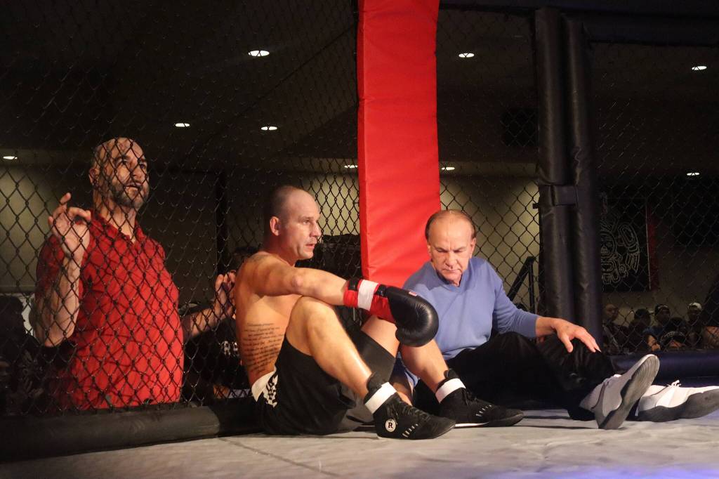 Tyson Duckworth (center) sits down in the corner of his ring, joining a call from the audience to extend his boxing match against Marco Reina to five rounds instead of three during the main event of AK Beatdown 36 on Saturday night at Elizabeth Peratrovich Hall. (Mark Sabbatini / Juneau Empire)