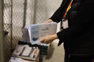 A city election work handles envelopes from the 2023 municipal election at the City and Borough of Juneau Ballot Processing Center. (Clarise Larson / Juneau Empire file photo)