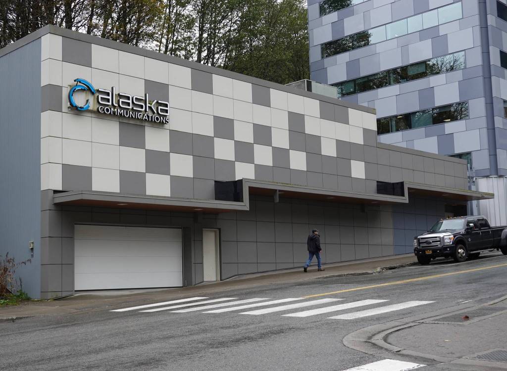 A man walks past the building housing private telecom company ACS on Main Street in downtown Juneau on Monday, Oct. 7, 2024. (Laurie Craig / Juneau Empire)