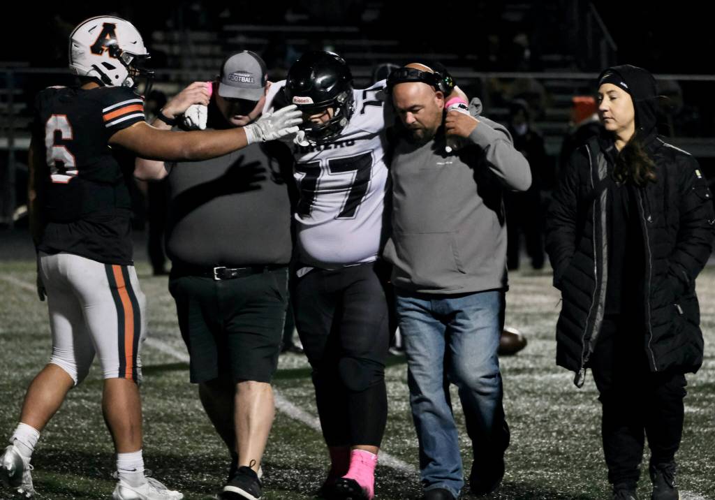 West Anchorage senior Zephaniah Sailele (6) offers support to Juneau junior Ricky Tupou (77) as he is helped off the field during the Huskies 20-13 loss to the Eagles in the 2024 ASAA State Football Playoffs on Saturday at West Anchorages Nest on Hillcrest. (Klas Stolpe/Juneau Empire)