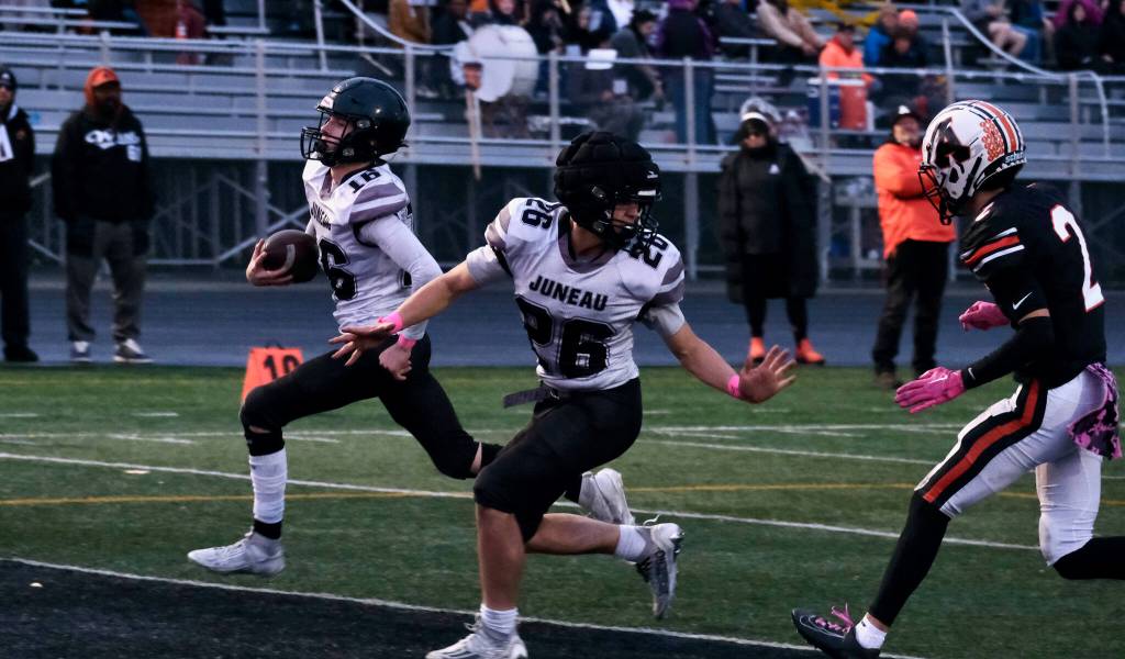 Juneau senior Caleb Ziegenfuss (16) scores as sophomore Jaxin Jim (26) blocks West Anchorage senior Ariel Sanchez (2) during the Huskies 20-13 loss to the Eagles in the 2024 ASAA State Football Playoffs on Saturday at West Anchorages Nest on Hillcrest. (Klas Stolpe/Juneau Empire)