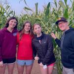 Glacier Swim Club athletes Emma Fellman, Valerie Peimann and Lily Francis stand with coach Scott Griffith in a corn field after competing in a meet in Lake Oswego, Oregon, over the weekend. (Photo courtesy Glacier Swim Club)