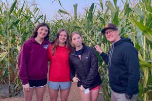 Glacier Swim Club athletes Emma Fellman, Valerie Peimann and Lily Francis stand with coach Scott Griffith in a corn field after competing in a meet in Lake Oswego, Oregon, over the weekend. (Photo courtesy Glacier Swim Club)