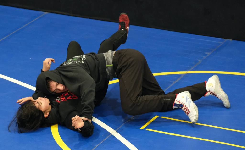 Senior Camden Messmer works a pin on freshman Nixie Schooler. during the Juneau-Douglas High School: Yadaa.at Kalé Crimson Bears wrestling team practice on Wednesday. (Klas Stolpe/Juneau Empire)
