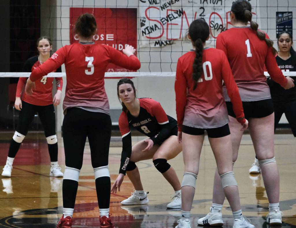 Juneau-Douglas High School: Yadaa.at Kalé senior Evelyn Richards (8), and juniors Cambry Lochhart (4) and Lavinia Maake (11) await a Wasilla serve during the Crimson Bears three-set loss to the visiting Warriors on Saturday at the George Houston Gymnasium. (Klas Stolpe/Juneau Empire)
