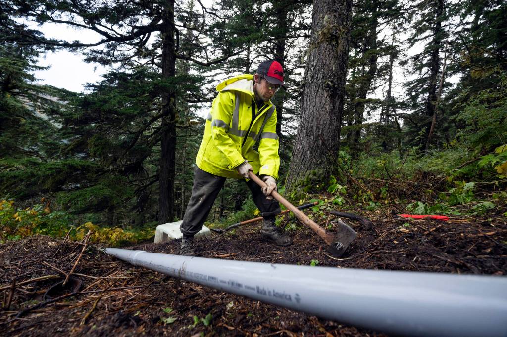 Kanaan Bausler, who works for the local power company, digs a trench for cables to supply a lysimeter, a device for measuring the amount of water transported through soil, on the side of Mount Roberts on Sept. 26, 2024. Deadly landslides are increasing around the world, but in parts of Alaska, maps of the hazards remain controversial. (Christopher Miller/The New York Times)