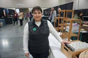 Michelle Sparck, director of Get Out The Native Vote, stands by her business booth on Saturday at the Alaska Federation of Natives convention in Anchorage. Sparck, wearing a button identifying her as a Cupik voter, is urging Alaska Natives to be more diligent about voting in both state and local elections. In addition to her voter-education work, Sparck has a beauty-products business, ArXotica, that she and her sisters founded. (Yereth Rosen/Alaska Beacon)