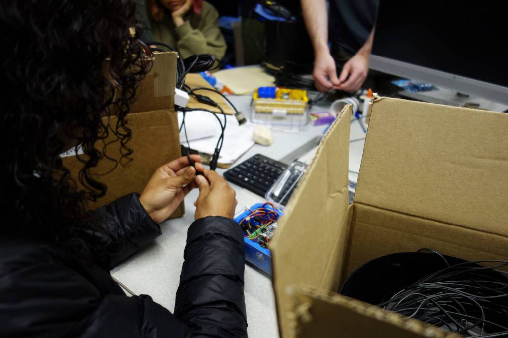 Hoonah Alaska Youth Stewards crew members plug sensors into WeatherChime environmental monitoring devices. (Photo by Zofia Danielson)