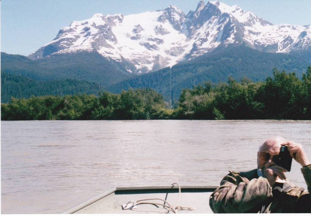In some locations a 20-foot wide border line was cut through vegetation. Here the late Vern Gilbertson is seen in about 1999 near the Taku River border cut in the background. (Photo courtesy of Steve Gilbertson)