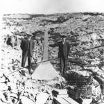 Secretary of Interior Walter Fisher and Alaska Territory Governor Walter Eli Clark (1909-1913) stand beside the boundary monument at White Pass in this undated photo taken near the White Pass and Yukon Route Railway that connects Skagway with Whitehorse, Yukon Territory, Canada. (ASL-P75-317)