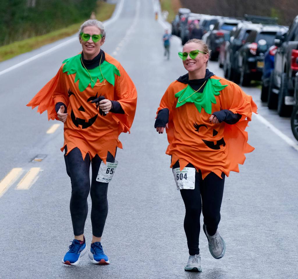 Melissa Anderson and Suzanne Morris finish the 5K race in running pumpkin attire at the Halloween Half Marathon on Saturday along North Douglas Highway. (Klas Stolpe / Juneau Empire)