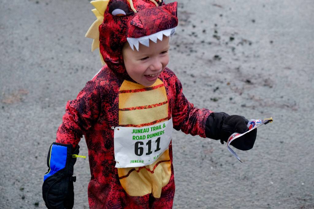 Harrison Mason, 3, is delighted with his ribbon for finishing the Halloween Half Marathon and 5K on Saturday along North Douglas Highway. (Klas Stolpe / Juneau Empire)